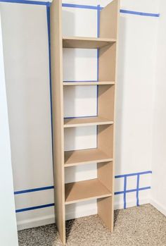 an empty shelf in the corner of a room with blue tape on the wall behind it