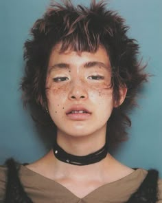 a woman with freckles on her face wearing a choker and looking at the camera