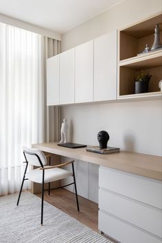 a white desk and chair in front of a window next to a shelf with a vase on it