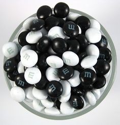 black and white candies in a glass bowl with the word m on it's side