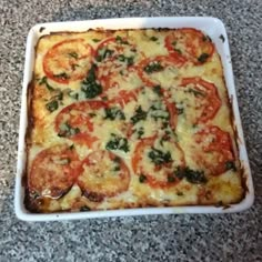 a square casserole dish with tomatoes and spinach on top, ready to be eaten