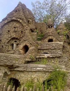 an old building made out of rocks and stone with some plants growing on the side