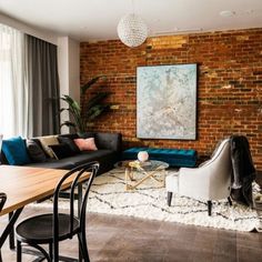 a living room filled with furniture and a brick wall behind the couch is a dining table