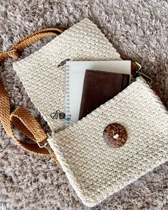 a white purse with a brown button on the side and a book in it's pocket