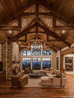 a large living room with high ceilings and wood flooring on the walls, along with stone fireplace mantels