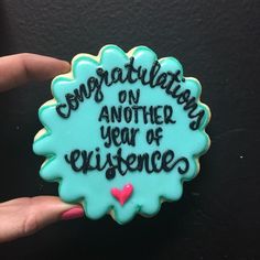 a cookie that says congratulations on another year of experience in blue icing with pink heart