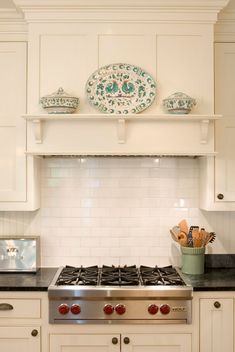 a stove top oven sitting inside of a kitchen next to white cabinets and counter tops