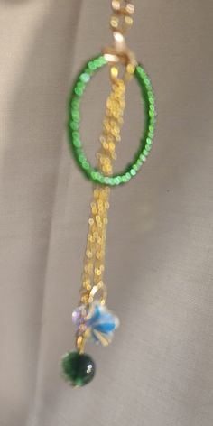 Green glass seed beads make the hoop hanging  from a gold earring hook pop.  Hanging from the center are two dainty gold colored chains holding a sparkling crystal on one and a green glass bead on the other.  Perfect to add to your outfit for the St Patrick’s Day Party Gold Glass Jewelry With Dangling Beads, Green Glass Beaded Chain Jewelry, Gold Beaded Necklaces With Czech Glass And Dangling Beads, Green Glass Jewelry With Beaded Chain, Gold Beaded Necklaces For May Birthstone, Green Round Jewelry With Tiny Beads, Green Jewelry With Tiny Beads, Green Tiny Beads Necklace For Party, Green Dangle Beaded Necklaces With Faceted Beads