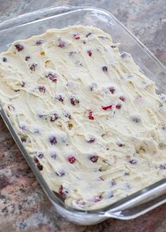 an uncooked cake in a plastic container on a counter top with cranberries