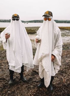 two people in white robes and hats standing next to each other with sunglasses on their faces