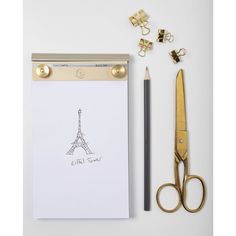 a clipboard with an eiffel tower drawn on it next to a pair of scissors