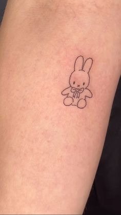 a small bunny tattoo on the left inner arm and leg, with an outline of a rabbit holding a bow in it's hand