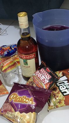 various snacks and drinks sitting on a table next to a blue container with liquid in it