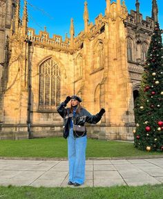 a woman standing in front of a large building with a christmas tree on the lawn