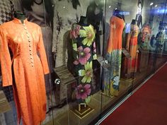 an orange dress and other clothing on display in a glass case