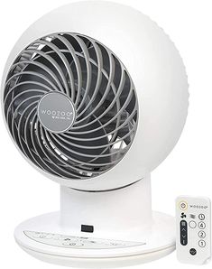 a white fan sitting on top of a table next to a remote control