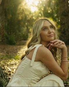 a woman sitting on the ground next to a tree