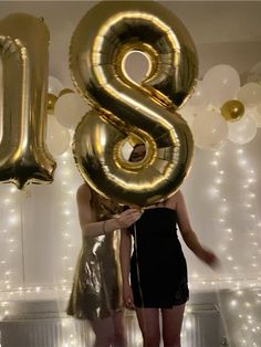 two women standing next to each other in front of balloons that spell out the number eight