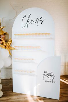 a white and gold wedding stationery set up on a wooden floor next to balloons