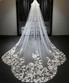 a wedding veil with white flowers on the bottom is shown in front of a mirror