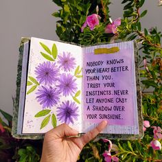 a hand holding an open book with flowers on it