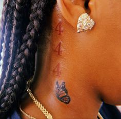 a close up of a person with tattoos on their neck and behind her ear is a butterfly