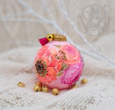 a pink ornament sitting on top of a white blanket with gold bells around it