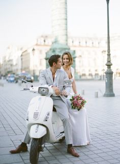 a man and woman are sitting on a scooter