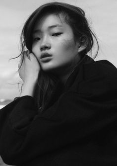 a black and white photo of a woman with her hair blowing in the wind, looking at the camera