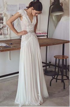 a woman standing in front of a table wearing a dress with lace on the back