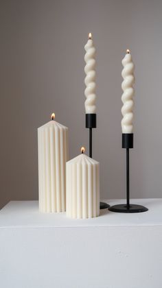 three candles sitting on top of a white table