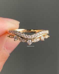 a hand holding a gold ring with three diamonds on it's sides and the top half of its band