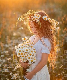 a girl in a white dress holding daisies