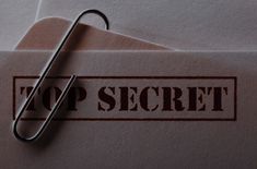 a close up of a paper clip on top of an envelope with the word top secret printed on it