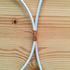 two white wires connected to each other on top of a wooden table next to an orange wire