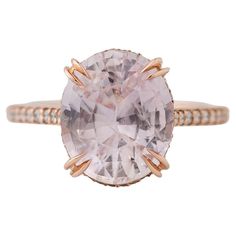 an oval shaped pink diamond ring with two rows of diamonds on the band, set in 18k rose gold