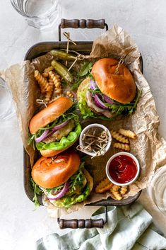 a tray filled with sandwiches and french fries next to some dipping sauce on the side