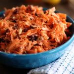 a blue bowl filled with shredded carrots on top of a table