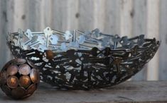 two metal bowls sitting next to each other on top of a wooden table and one has a soccer ball in it