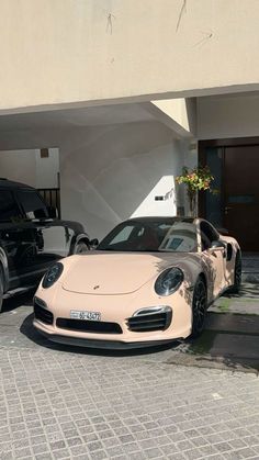 two porsches are parked in front of a building with their doors open and one is black