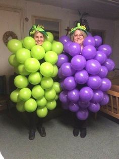 two women standing next to each other with balloons in the shape of grapes on their heads