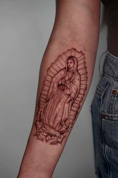 a woman's arm with a tattoo of the virgin mary and jesus on it