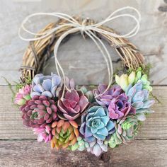 a bunch of succulents sitting on top of a wooden table next to a wreath