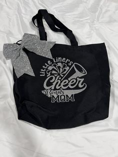 a black tote bag with silver glitter bow on it's handle and the words live, love, cheer, and mom