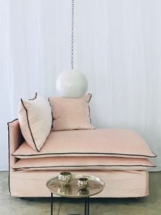 a pink couch with pillows on it and a white ball hanging from the ceiling above