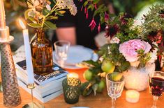 the table is set with candles, plates and flowers in vases on top of books