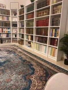 a room filled with lots of books on top of a book shelf next to a rug