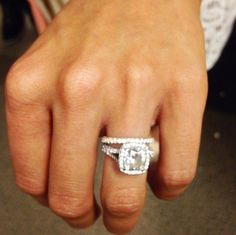 a woman's hand with a diamond ring on top of her finger and an engagement band