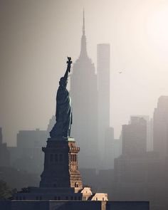 the statue of liberty is surrounded by tall buildings