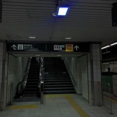 an escalator in a subway station with stairs leading up to the exit door